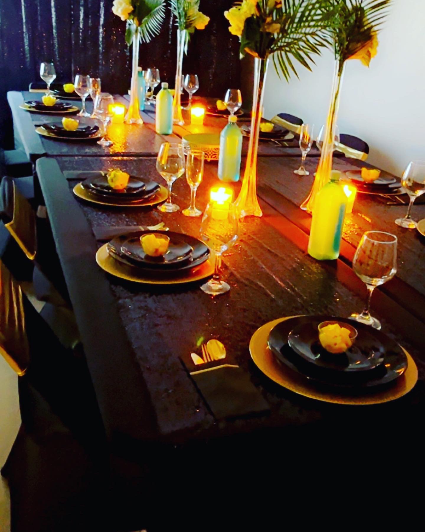 Elegant birthday dinner tablescape with black linens, gold chargers, tall florals, and candlelight