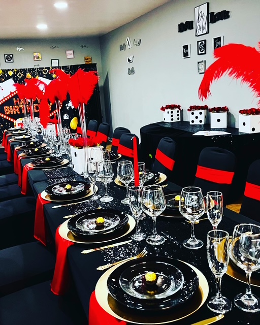 Casino-themed birthday party tablescape with black linens, red feathers, and gold accents
